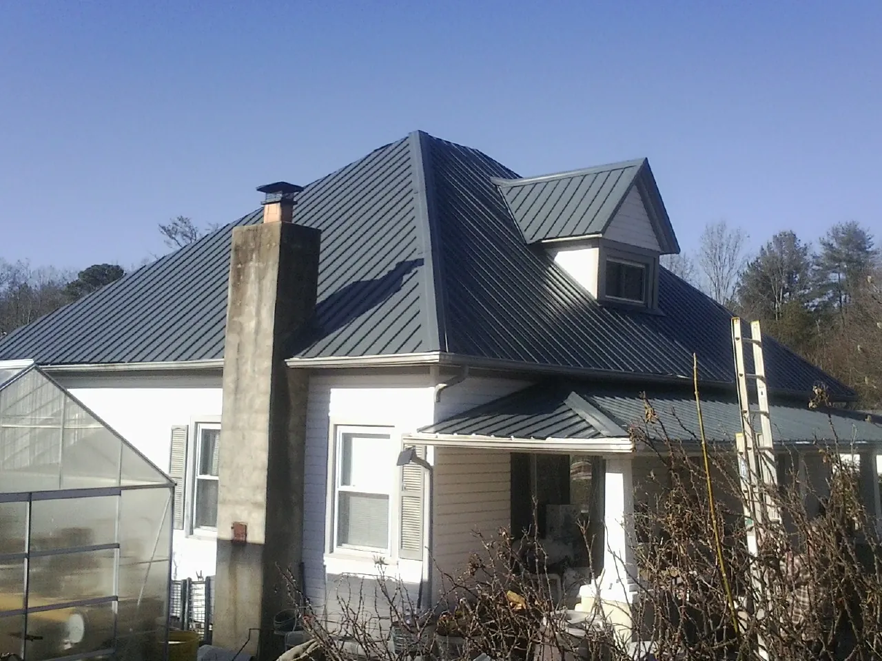 Dark blue standing seam metal roof on a white farmhouse with dormer — Slate & Tile Roof Repair by Roofing Brothers in Kendall