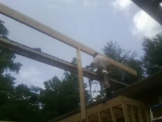Carpenter setting a ridge beam over a new addition frame — Ice Dam Removal by Roofing Brothers in Kendall