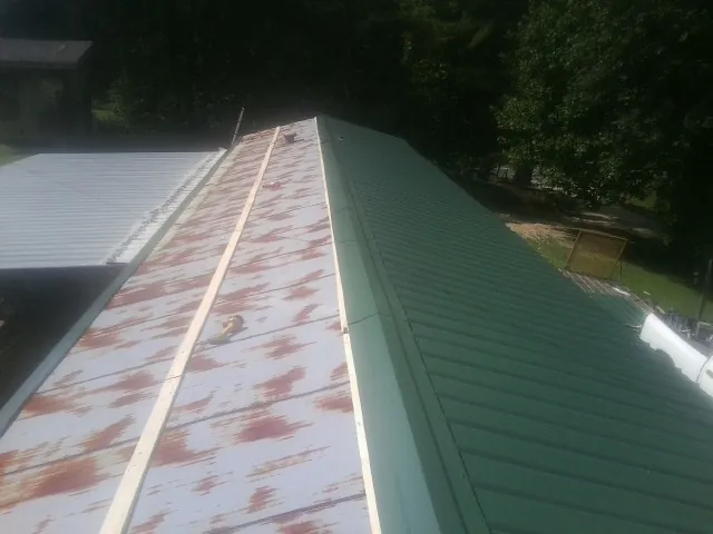 Old rusted panels beside newly installed green metal roofing — Wind Damage Roof Repair by Roofing Brothers in Kendall