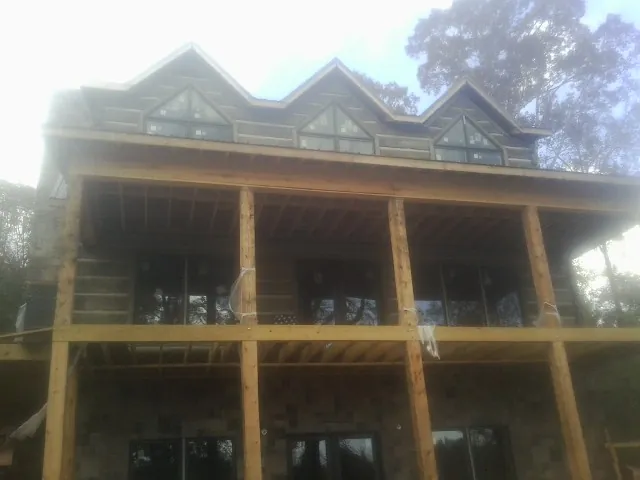 Dormers and porch framing on a large log home under construction — Roof Coating work by our crew in Kendall