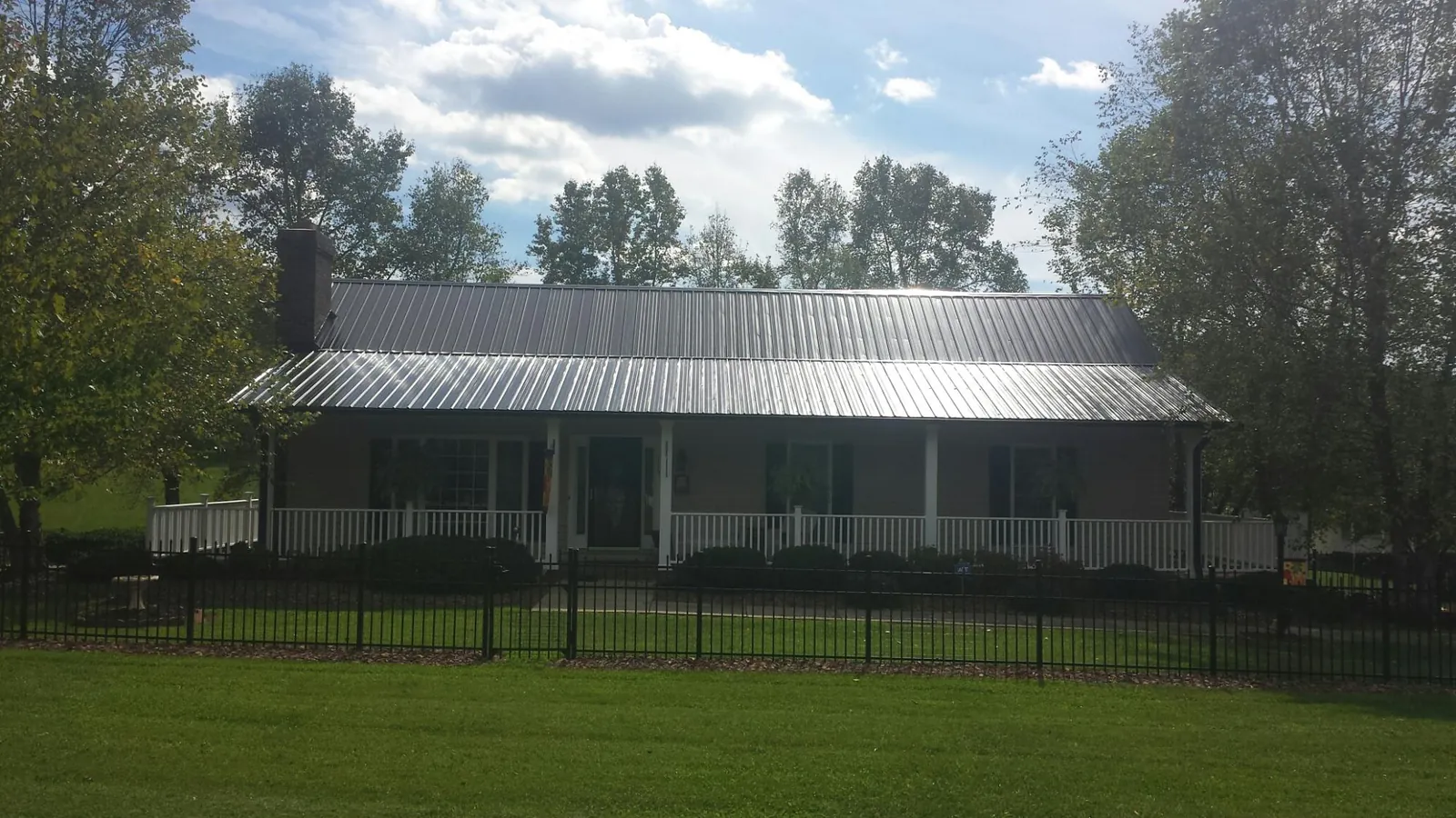 Gray metal roof on a brick ranch with a full width front porch — Gutter Guard Installation work by our crew in Kendall