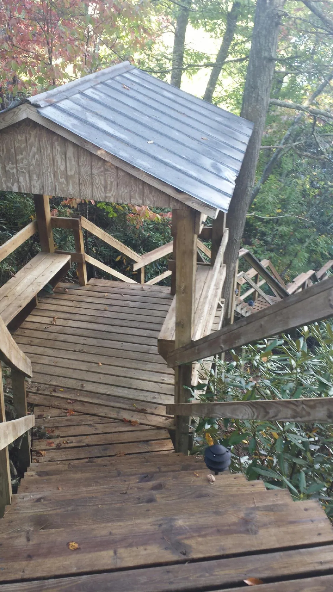 Metal roofed shelter over wooden steps on a wooded walkway — Skylight Repair & Installation work by our crew in Kendall
