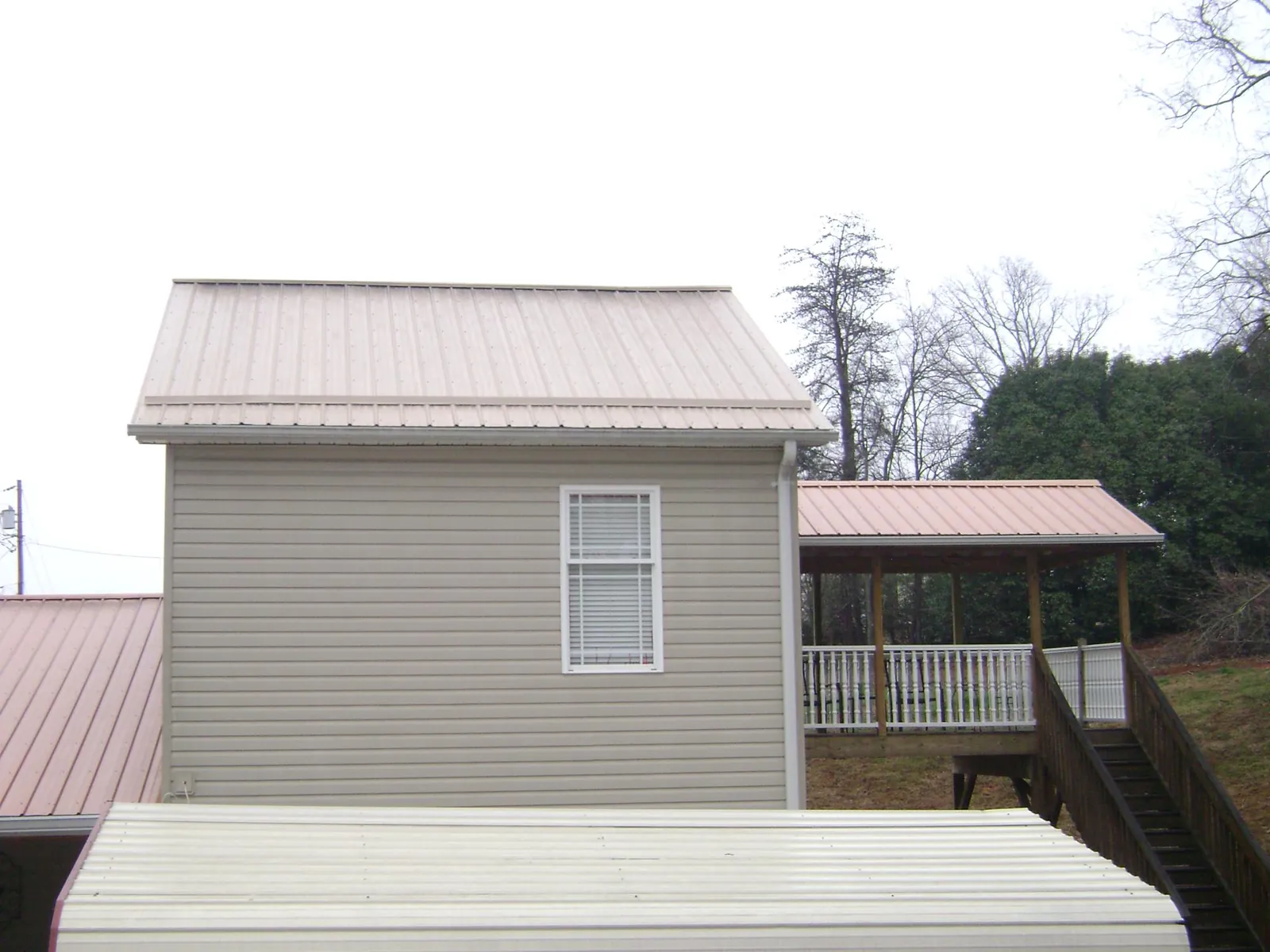 Tan metal roofs on a two story addition and attached porch, from a Roof Replacement job in Kendall
