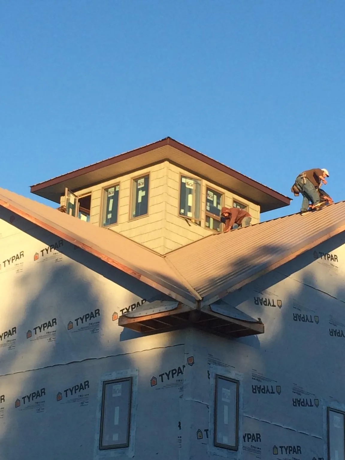 Roofers working around a rooftop cupola on a new metal roof at sunset — Roof Waterproofing in Kendall by Roofing Brothers